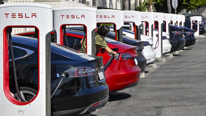 Des bornes de recharge Tesla et des voitures qui y sont branchées.