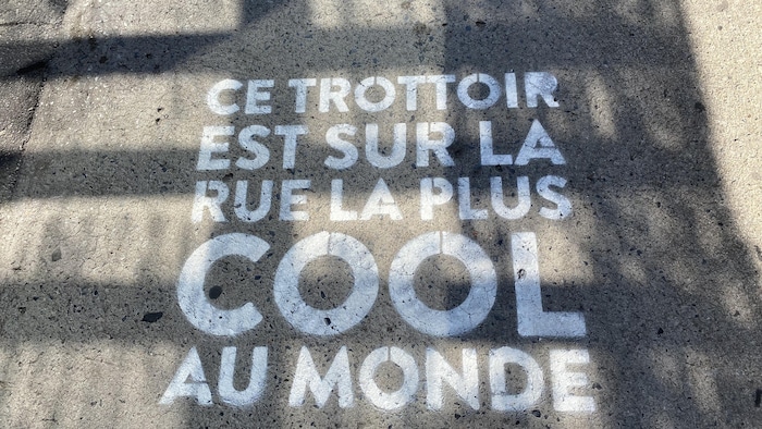 Sur un trottoir de la rue Wellington de Montréal, on peut lire « Ce trottoir est sur la rue la plus COOL du monde ».