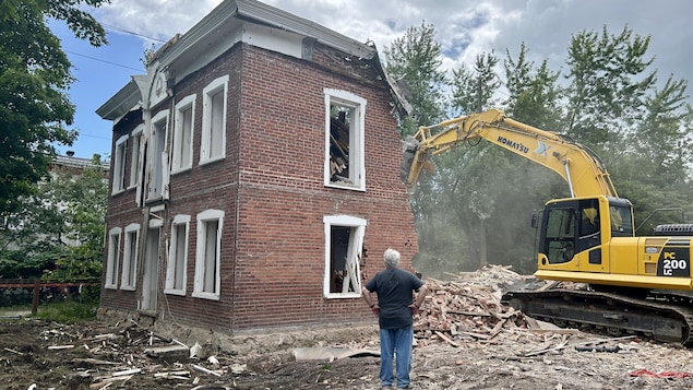 Un homme regarde le gîte être détruit.