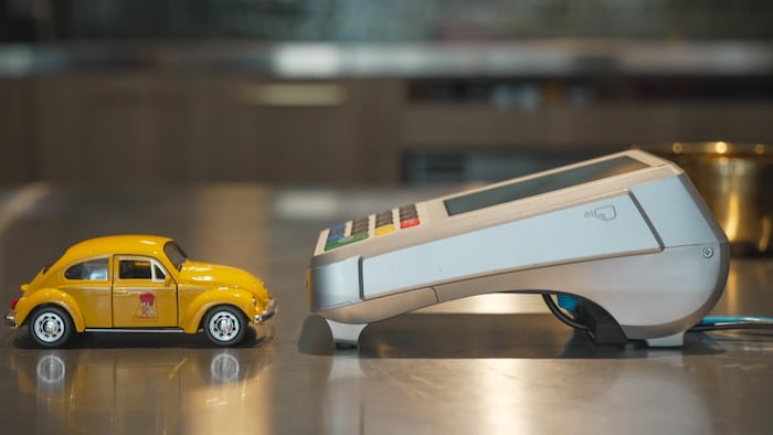 Une voiture St-Hubert miniature à côté d'un terminal de paiement.