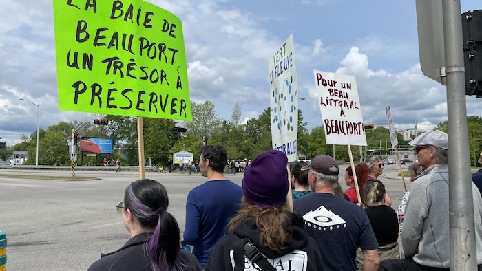 Une dizaine de personnes. Une femme tient une pancarte où il est écrit « La baie de Beauport, un trésor à préserver ».