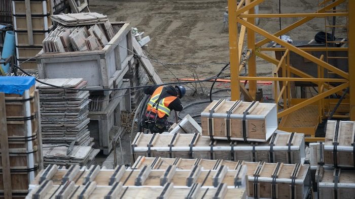 Un travailleur à l'ouvrage au milieu de boîtiers sur un chantier de construction.