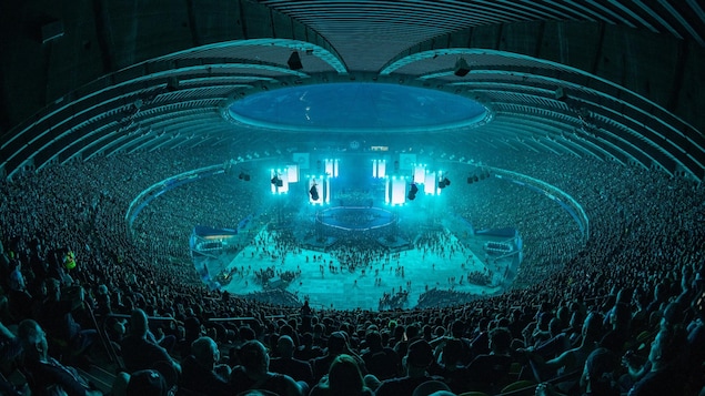 Foule monstre à l'intérieur du Stade olympique dans un éclairage bleuté.
