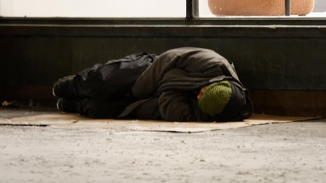 Un homme couché au sol, tentant de se couvrir autant que possible.