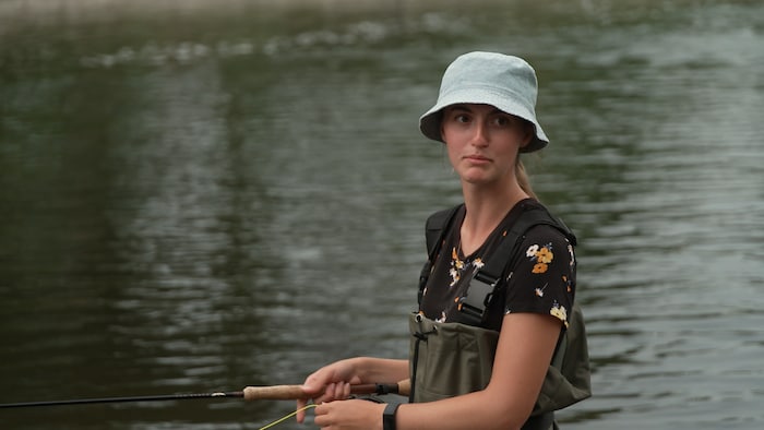 Une femme pêche dans une rivière.