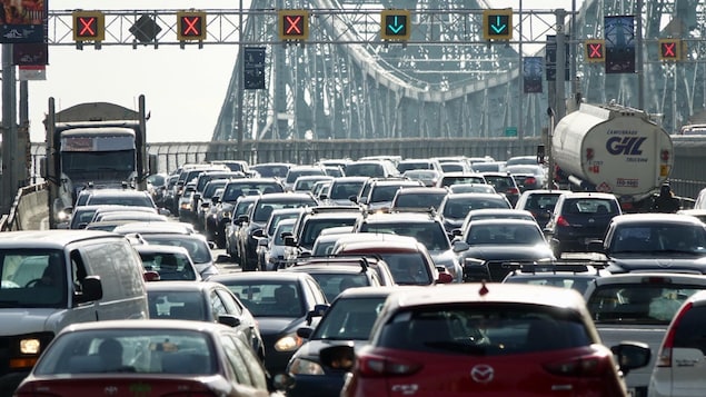 Plusieurs véhicules sont pris dans la congestion routière du pont Jacques-Cartier, à l'heure de pointe matinale à Montréal, alors qu'on voit les feux de circulation signalant les voies ouvertes et fermées dans les deux sens.