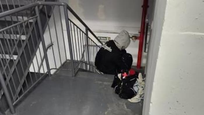 Une personne occupe l'escalier d'un immeuble à condos de la rue Charlotte, ses affaires posées près d'une tâche d'urine.