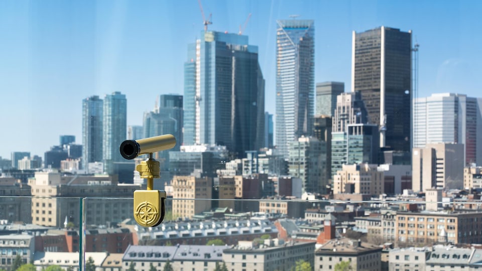 Un viseur sur une rembarde en verre pointe vers le centre-ville de Montréal.