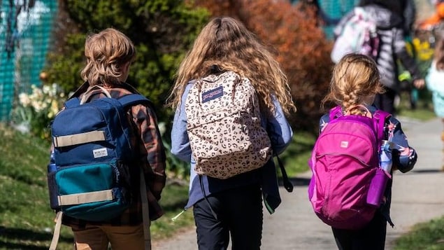 Des enfants portant des sacs à dos en route vers l'école.