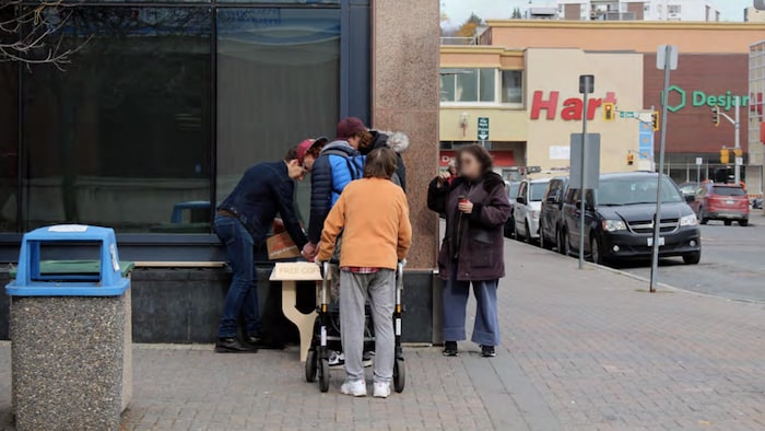 Une table temporaire installée sur le coin d'une rue où des passants prennent un café.