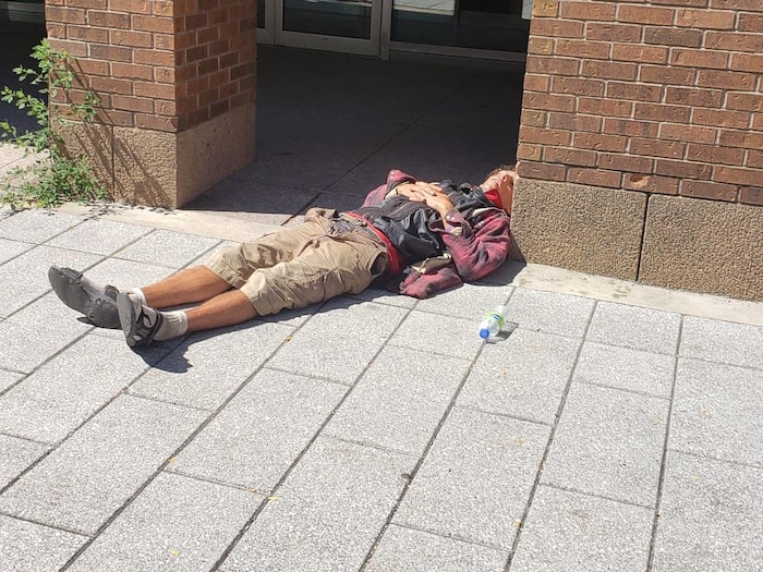 Un homme dort à terre, en face du Palais des congrès.