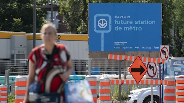 Un panneau annonce une future station de métro sur un chantier de construction.