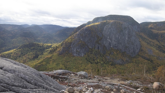Une vallée surplombée par des montagnes verdoyantes et rocailleuses, en été.