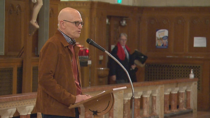 Serge Savaria parle dans un micro à l'église des Saints-Martyrs-Canadiens.