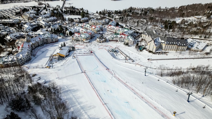 Vue d'avion de l'arrivée d'une piste de ski qui se termine au pied d'une village enneigé