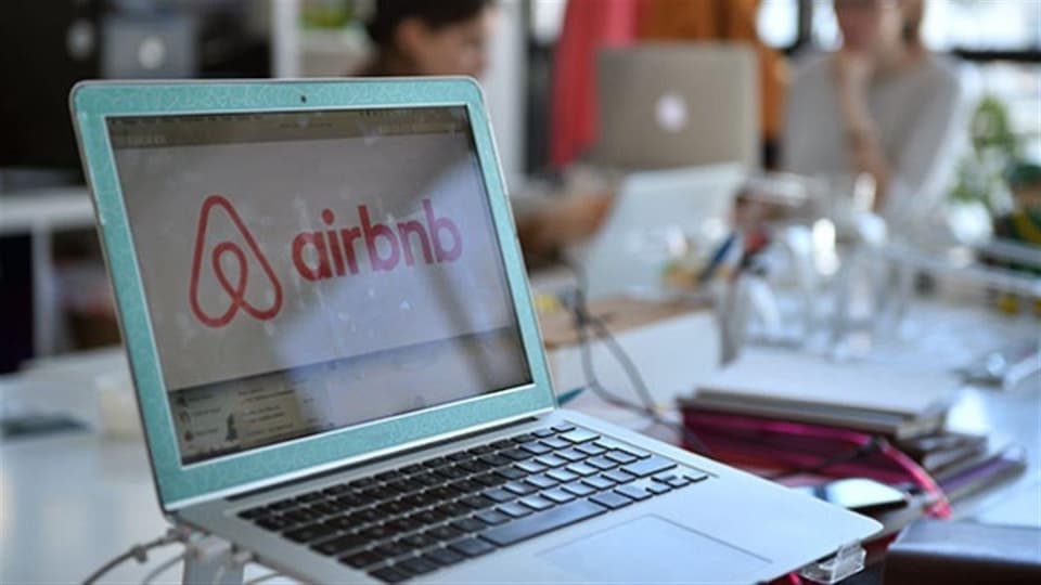 Le logo d'Airbnb s'affiche sur un écran d'ordinateur portable dans une salle de travail.