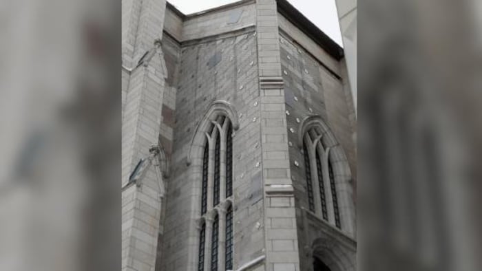La façade d’une église gothique recouverte en partie par des filets d’acier fixés par des ancrages constitués de tiges filetées.