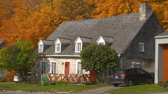 La maison d'André Tanguay en pierres avec ses deux portes rouges et ses nombreuses fenêtres et lucarnes.