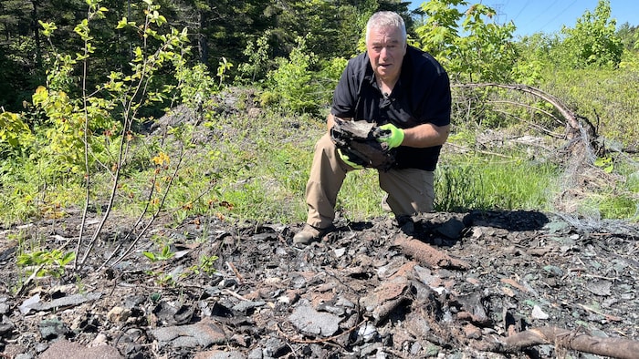 Marcel Poiré, président de PurNat, tient dans ses mains des bardeaux d'asphalte jetés dans la nature.