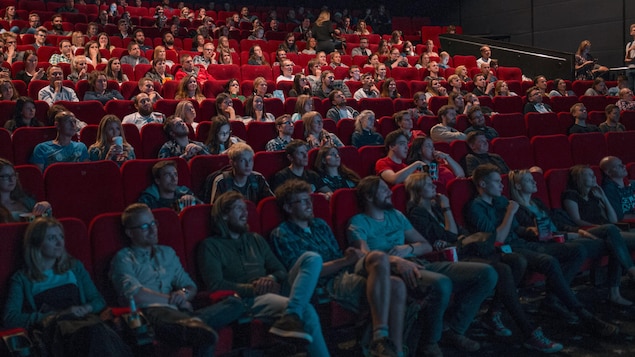 Des spectateurs regardent un film dans une salle de cinéma.
