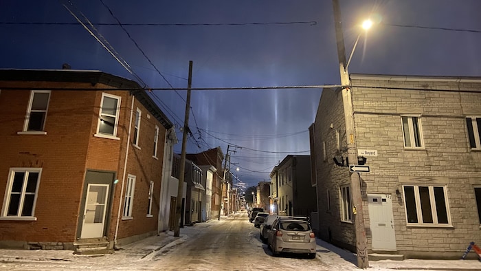 Des colonnes de lumières semblables à des aurores sont visibles dans le ciel au dessus des bâtiments.