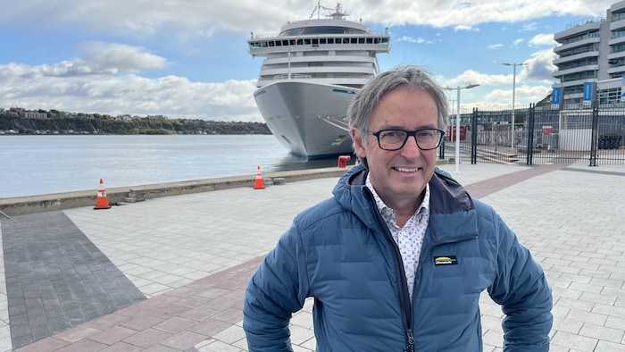 René Trépanier sourit pour la photo sur un quai de Québec, devant un bateau de croisière.