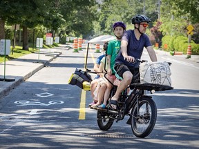 Benjamin Wallace, with his children on the back, was one of the early users of a bike path being created along Terrebonne St. in the N.D.G. district of Montreal on June 25.