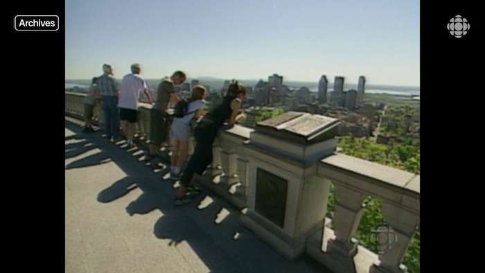 Quelques personnes regardent la vue sur le centre-ville de Montréal au belvédère Kondiaronk du mont Royal.
