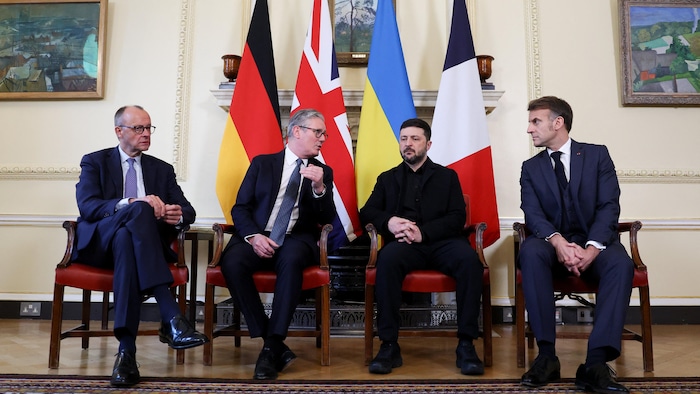 Le chancelier allemand Friedrich Merz, le premier ministre britannique Keir Starmer, le président ukrainien, Volodymyr Zelenskiy et le président français Emmanuel Macron assis dans une salle.