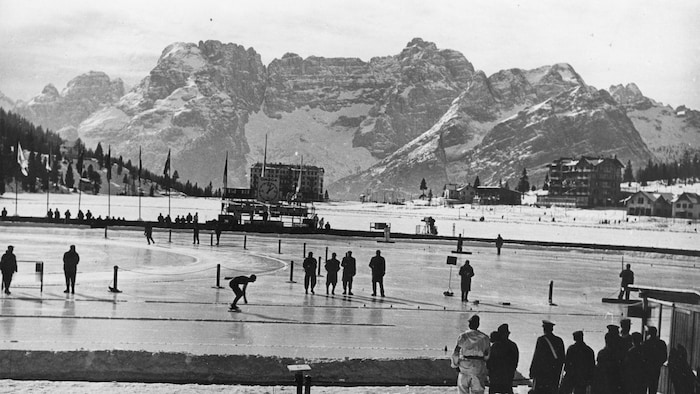 Une patinoire à ciel ouvert est couronnée par une chaîne de montagnes enneigée en arrière-plan.