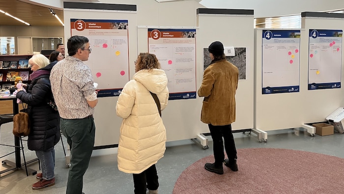 Des personnes consultent les panneaux informatifs dans l'atrium de la bibliothèque.